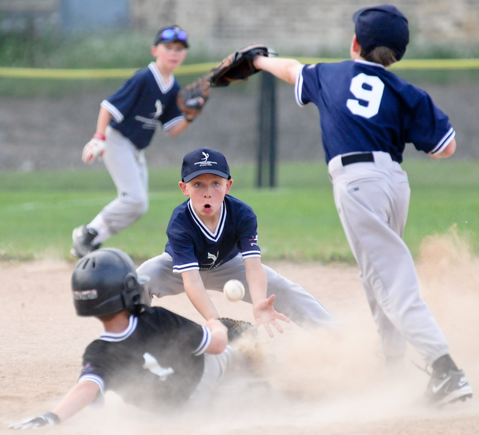 Austin Tess of the Bandits slides safely into second as Jackson Schmidt and Nathan Muck, (9) of Orthopaedic Associates reach for the ball.
